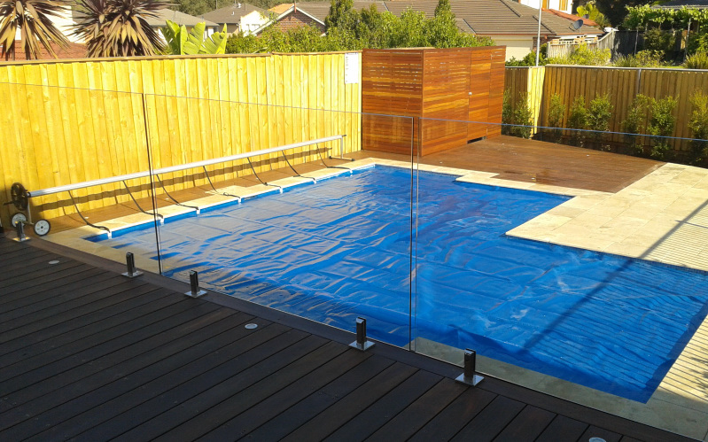 Swimming pool with cover and glass fencing