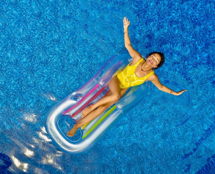 Happy woman on a pool float relaxing in the pool