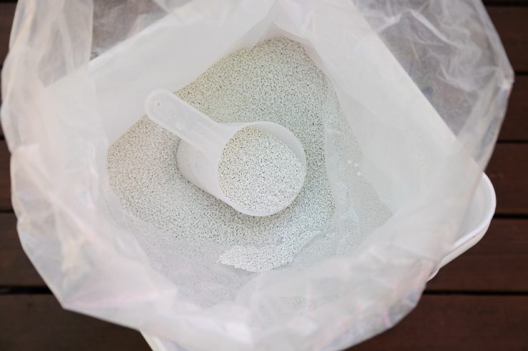 Bucket of granular powder chlorine shock for hot tubs with a scoop.