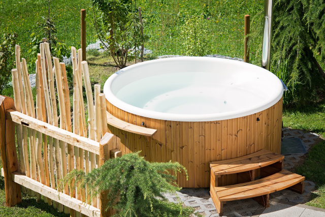Wooden outdoor hot tub in a garden.