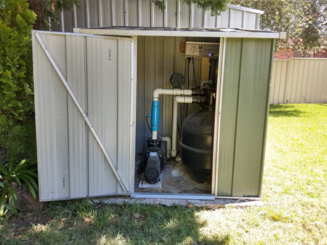 Enclosure shed for pool equipment system n the backyard.