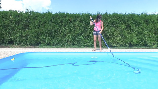 A woman vacuuming the swimming pool floor