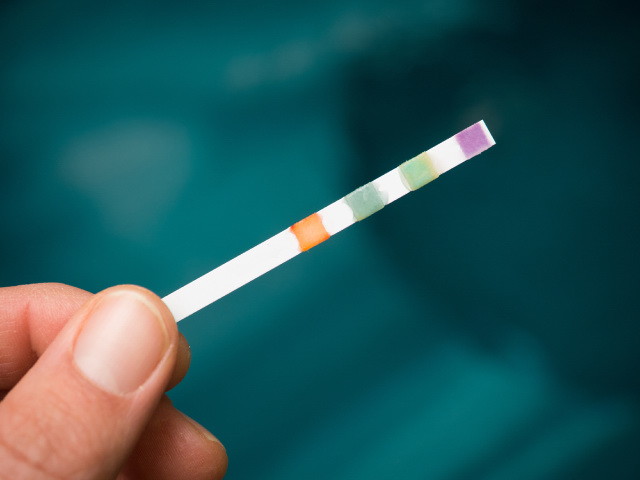 A man holding a test strip to test hot tub water.