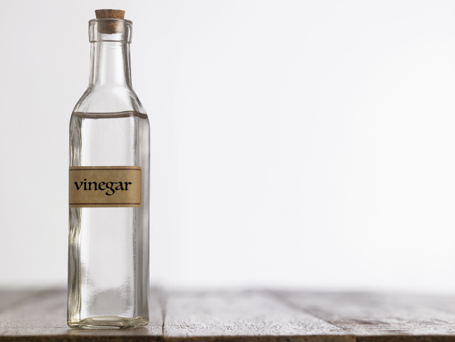 white vinegar in a clear bottle with cork cap on a wooden table