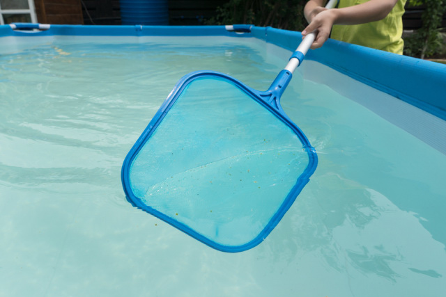 Manually collecting dirt and debris using a net skimmer.