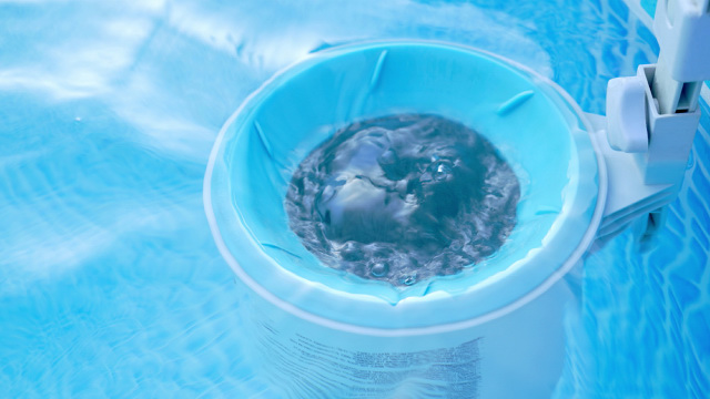 Close up view of an above-ground pool skimmer collecting dirt and trash.