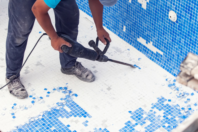 Removing pool tiles using electric tool.