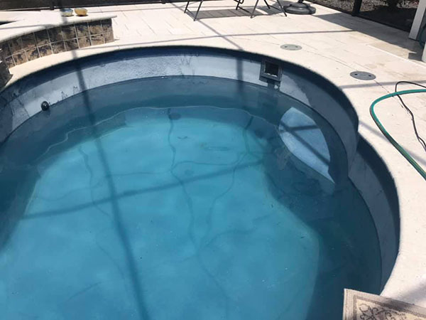 Inground fiberglass pool with white calcium scale around waterline.
