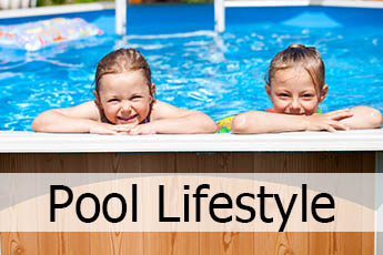 Two small girls in an above ground swimming pool smiling.